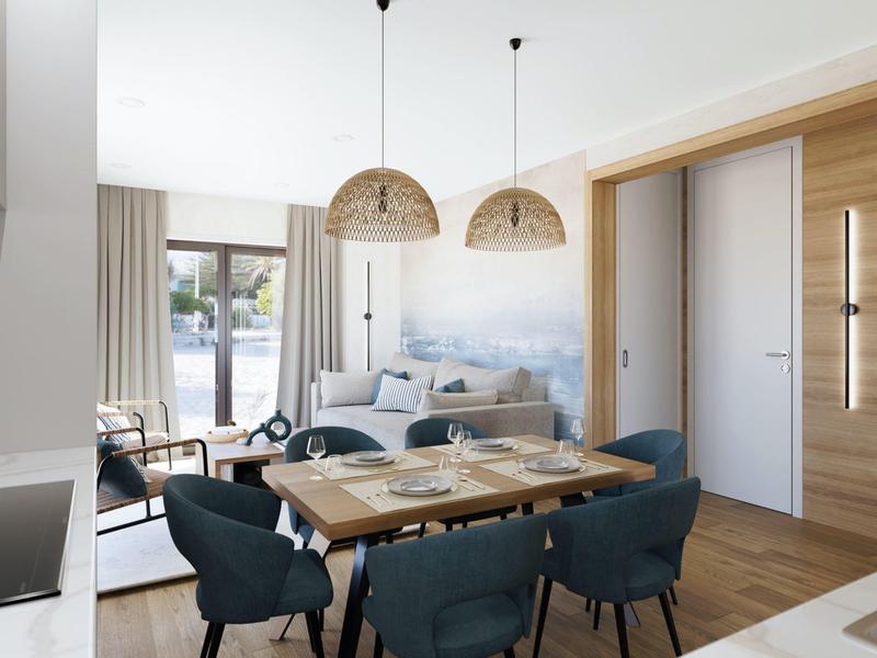 Moderně zařízený obývací pokoj s jídelním stolem, modrými židlemi a velkými okny s výhledem ven.