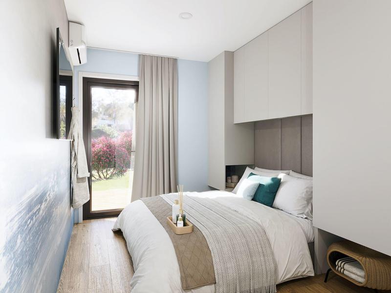 Světelný hotelový pokoj s manželskou postelí, střešním oknem a terasovými dveřmi s výhledem ven.