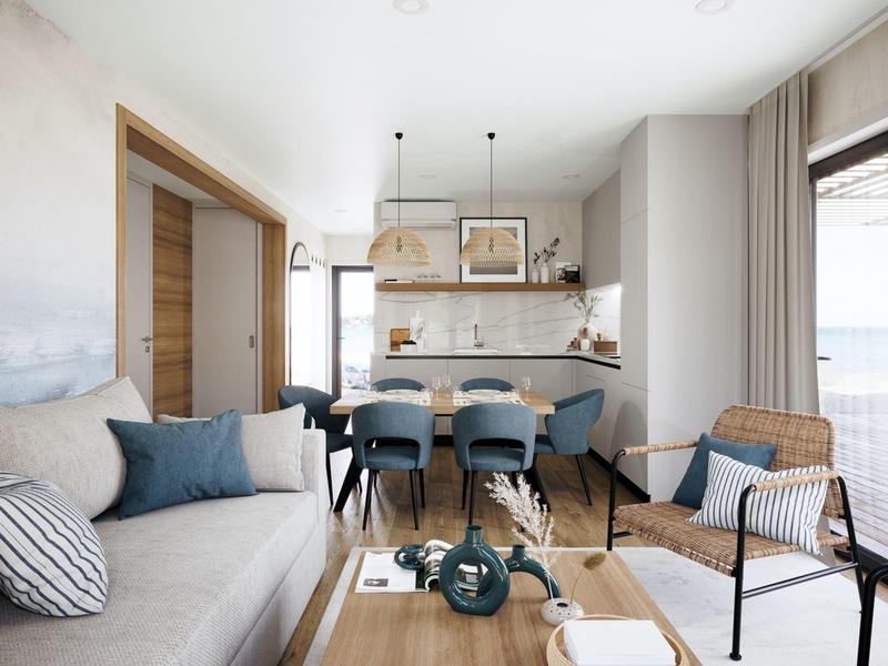 Moderní obývací prostor s pohovkou, jídelní částí a otevřenou kuchyní v světlých tónech.