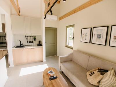 Bright living room with gray sofa, small wooden table, and modern kitchenette.