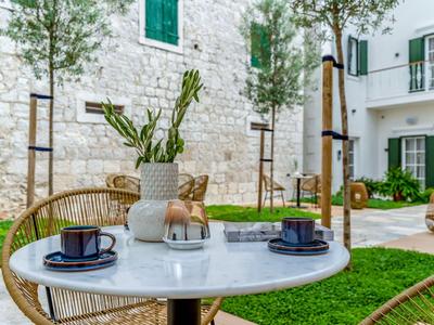 Tisch mit zwei Kaffeetassen und Vase in mediterranem Innenhof mit weißen Steinhäusern.