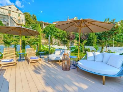 Gemütliche Outdoor-Loungemöbel mit Sonnenschirmen auf Holzterrasse bei sonnigem Wetter.