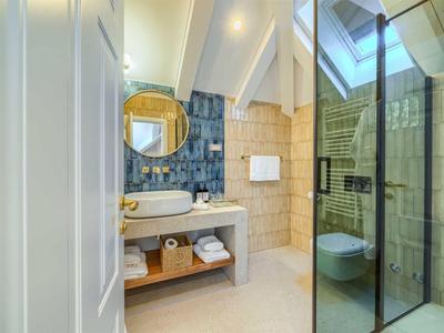 Modernes Badezimmer mit blauen Fliesen, Waschbecken, Spiegel und begehbarer Dusche.