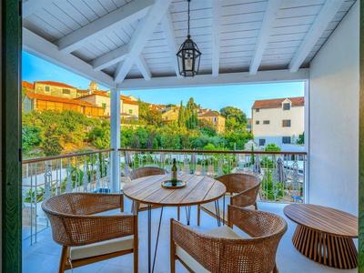 Balkon mit Rundtisch und vier Stühlen mit Blick auf grüne Umgebung und Häuser