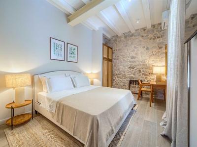Helles Hotelzimmer mit Doppelbett, Holzboden und rustikaler Steinwand.