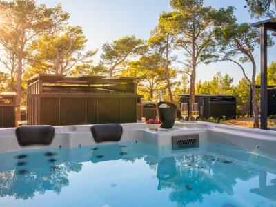 Moderne Whirlpool-Terrasse mit Wasserbecken und Sonnenuntergang bei Bäumen.