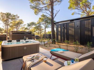 Moderne Terrasse mit Whirlpool, Sonnenliegen und Bäumen in einer ruhigen Umgebung.