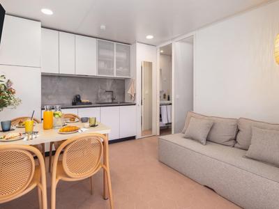 Modern eingerichtete kleine Küche mit Esstisch und gemütlichem Sofa in hellem Zimmer.
