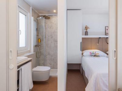 Kompaktes Hotelzimmer mit Dusche, Toilette und Einzelbett, minimalistisch eingerichtet.