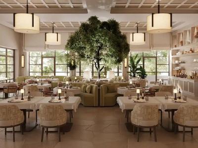 Helles, modernes Restaurant mit runden Tischen, beigen Stühlen und einer großen zentralen Pflanze.