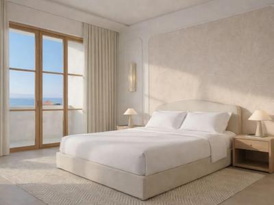 Helles Schlafzimmer mit Doppelbett und Blick auf das Meer durch große Fenster.