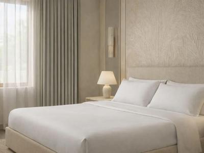 Modernes Hotelzimmer mit großem Bett, weißen Bettwäsche und einem Nachttisch mit Lampe.
