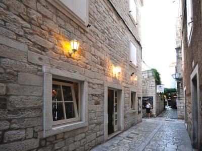 Enge Gasse mit Kopfsteinpflaster und beleuchteten Fenstern an steinernen Gebäuden.