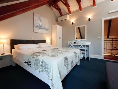 Gemütliches Hotelzimmer mit Doppelbett, Schreibtisch, dunkelblauem Teppich und Dachschräge.