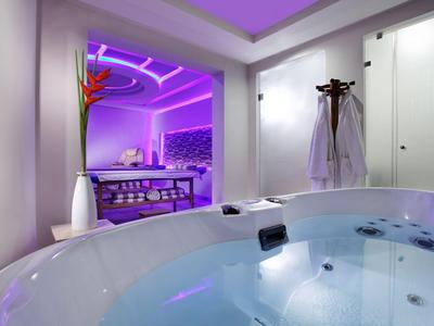 Luxuriöser Whirlpool in einem modernen Spa-Bereich mit violetter Beleuchtung und entspannendem Ambiente.