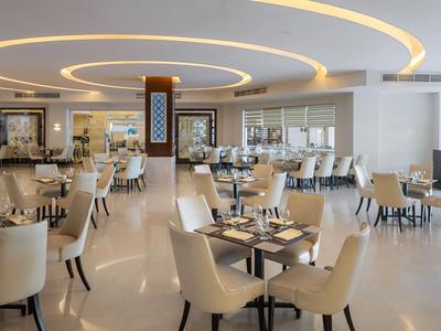 Helles, modernes Restaurant mit runden Deckenleuchten und elegantem Mobiliar in neutralen Farben.