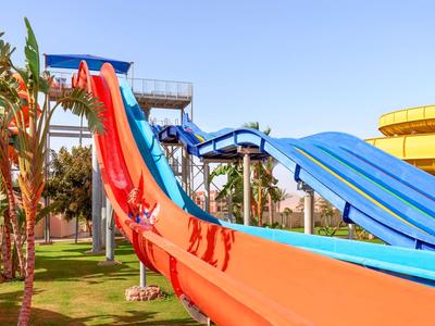 Mehrere bunte Wasserrutschen in einem Wasserpark mit grünem Gras und blauen Himmel.