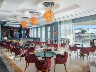 Eleganter Hotelrestaurantbereich mit rot gemusterten Stühlen und großen Fenstern mit Blick auf einen Pool.