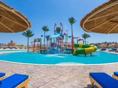 Wasserpark mit bunten Rutschen und Sonnenschirmen an einem Hotelpool bei Sonnenschein.