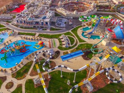 Vogelperspektive auf einen bunten Freizeitpark mit Wasserrutschen, Pools und Fahrgeschäften.
