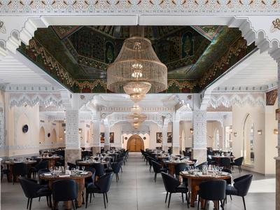 Eleganter Hotel-Speisesaal mit weißen Bögen, Kronleuchtern und gedeckten Tischen.
