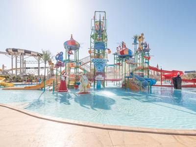 Kinder-Wasserspielplatz mit farbenfrohen Türmen und Rutschen in einem Hotelpool unter klarem Himmel.