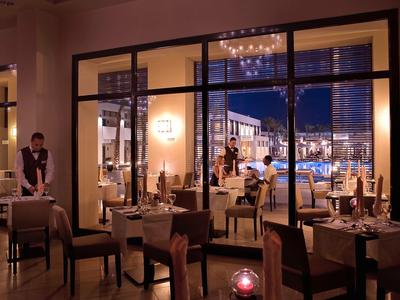 Elegantes Restaurant mit gedeckten Tischen und Blick auf den nächtlichen Innenhof.