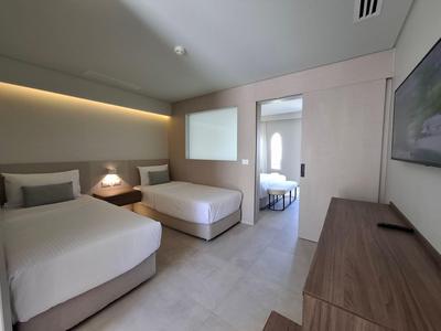 Modernes Hotelzimmer mit zwei Einzelbetten, trennbarem Raum und minimalistischem Design.