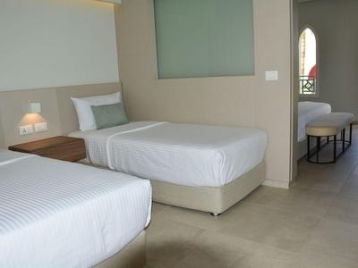 Hell eingerichtetes Hotelzimmer mit zwei Einzelbetten und Sicht auf Balkon mit Sitzgelegenheit.