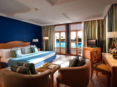 Geräumiges Hotelzimmer mit Doppelbett, Sitzbereich und Balkon mit Blick auf Wasser.