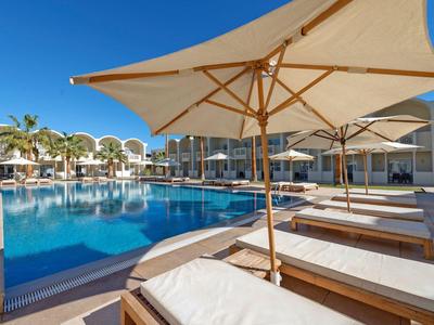 Moderner Hotelpool mit weißen Sonnenschirmen und Liegen unter blauem Himmel.