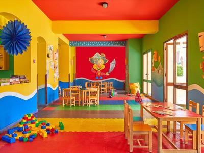 Bunter, kinderfreundlicher Raum mit Tischen, Stühlen, Bauklötzen und bunten Wänden in einem Hotel.