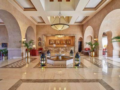Elegante Hotellobby mit Marmorboden, Sitzbereichen, großen Bögen und warmem Beleuchtungskonzept.