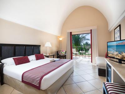 Modernes Hotelzimmer mit Doppelbett, Zugang zu Balkon und Blick auf den Garten.