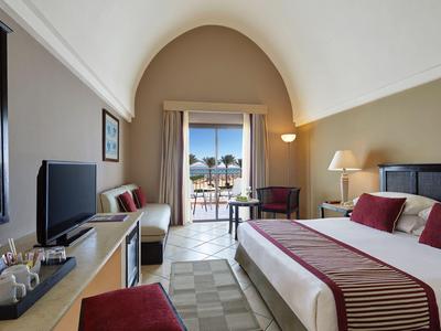 Elegantes Hotelzimmer mit großem Bett, Balkon und Blick auf das Meer bei Tageslicht.