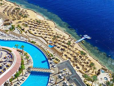 Piscina e lettini in un hotel sul mare blu con spiaggia sabbiosa.