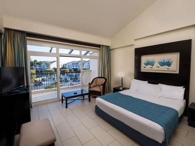 Camera d'hotel moderna con letto grande e balcone con vista su acqua e case.