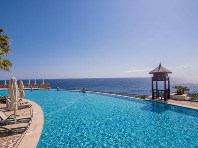 Piscina a sfioro con lettini e vista sul mare in una giornata limpida e soleggiata.