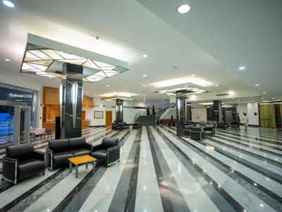 Große Hotellobby mit glänzendem Marmorfußboden, modernen Sitzbereichen und heller Beleuchtung.