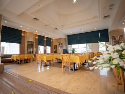 Helles Restaurant mit Holztischen und Stühlen, großen Fenstern und weißen Wänden.