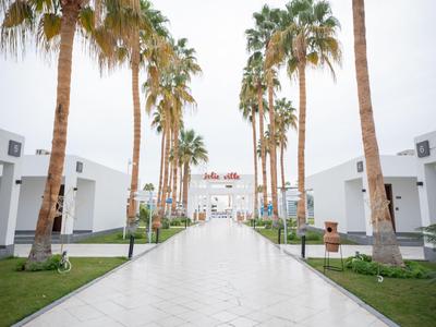 Breite Promenade mit Palmen und weißen Gebäuden, in einem Hotel-Resort-Stil.