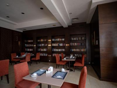 Modern eingerichtetes Hotelrestaurant mit dunklen Holzmöbeln und orangen Stühlen.