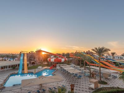 Wasserpark mit mehreren bunten Rutschen und Pools bei Sonnenuntergang in einem Hotelresort.