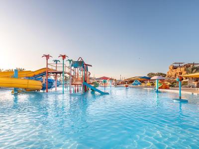 Großer Wasserpark mit Rutschen und Spielgeräten bei klarem Himmel und Sonnenschein.
