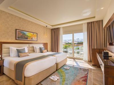 Modernes Hotelzimmer mit zwei Betten, Balkon und Meerblick bei Tageslicht.