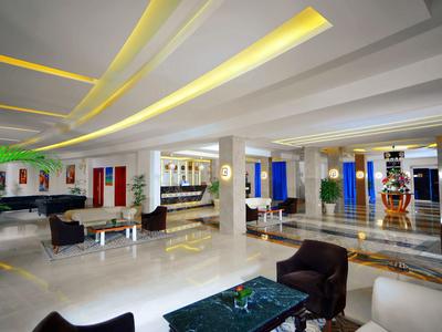 Moderne Hotellobby mit hellem Boden, bequemen Sesseln und stilvollen Deckenleuchten.