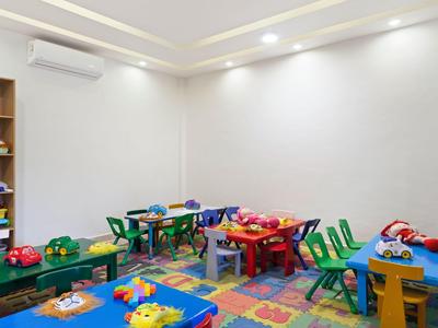 Buntes Kinderspielzimmer mit Tischen, Stühlen und Spielzeug in einem Hotel oder Ferienhaus.
