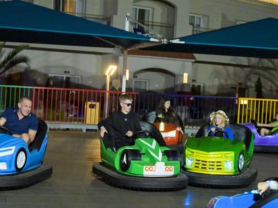 Vier Personen fahren mit bunten Bumpercars in einem überdachten Bereich eines Hotels.