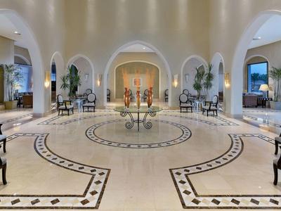 Großer Hotellobby mit zentralem Blumentisch, eleganten Stühlen und dekorativen Pflanzen.