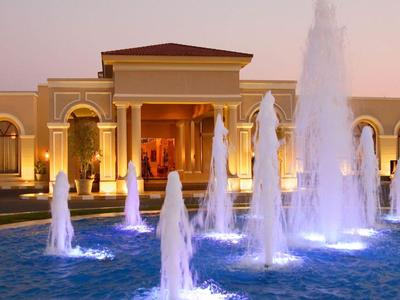 Ein Hotel mit beleuchtetem Springbrunnen und warmem Abendhimmel im Hintergrund.